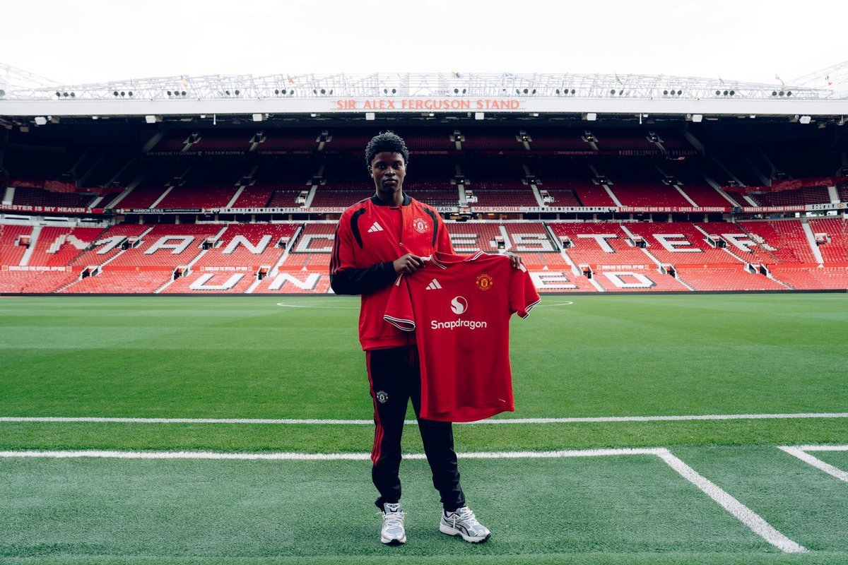 Karim Cassim sostiene una camiseta del Manchester United en Old Trafford