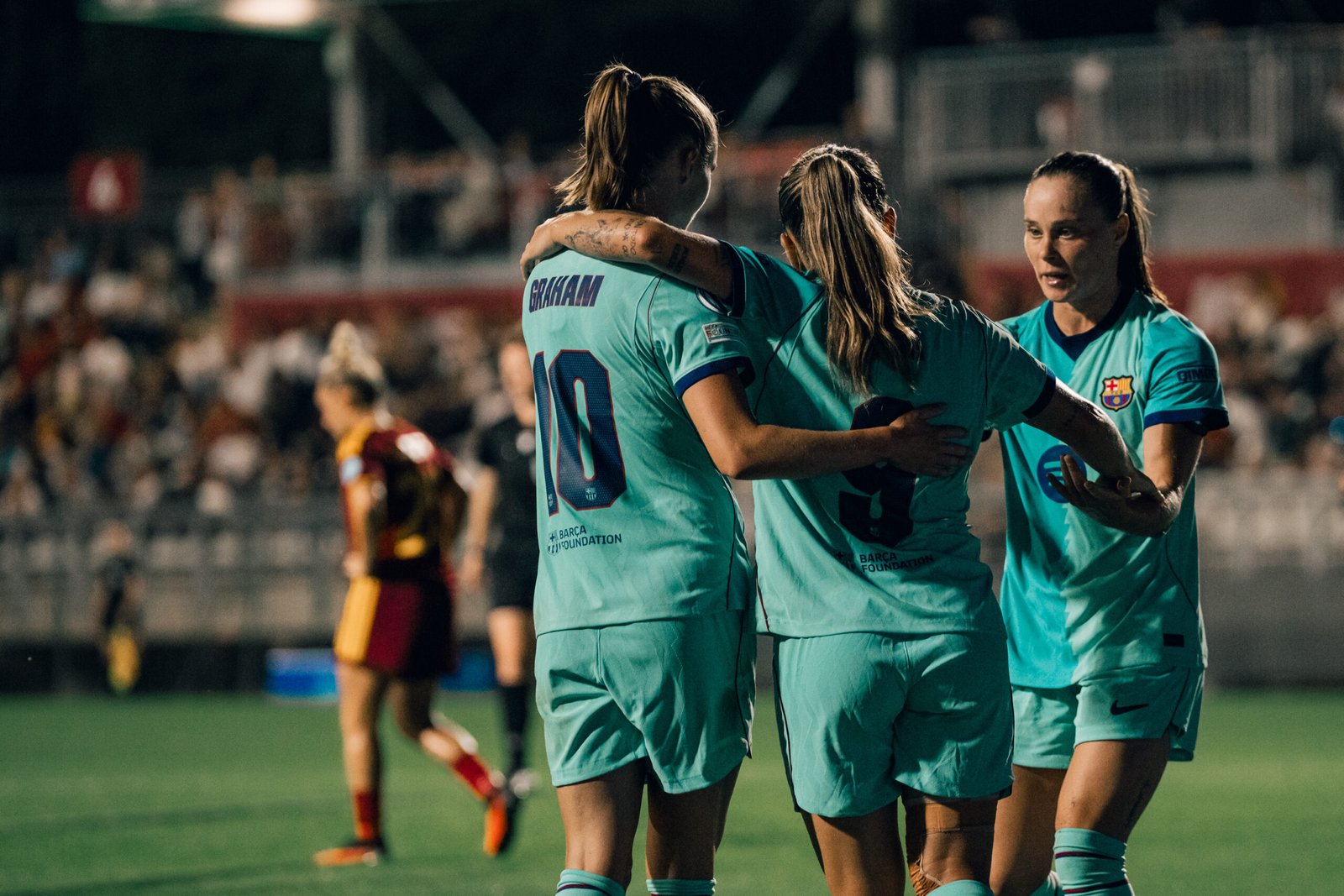 Graham Hansen se abraza a una compañera del Barcelona ante una tercera jugadora durante el partido frente a la Roma.