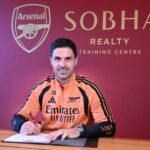 Mikel Arteta sentado ante un documento en el centro de entrenamiento del Arsenal