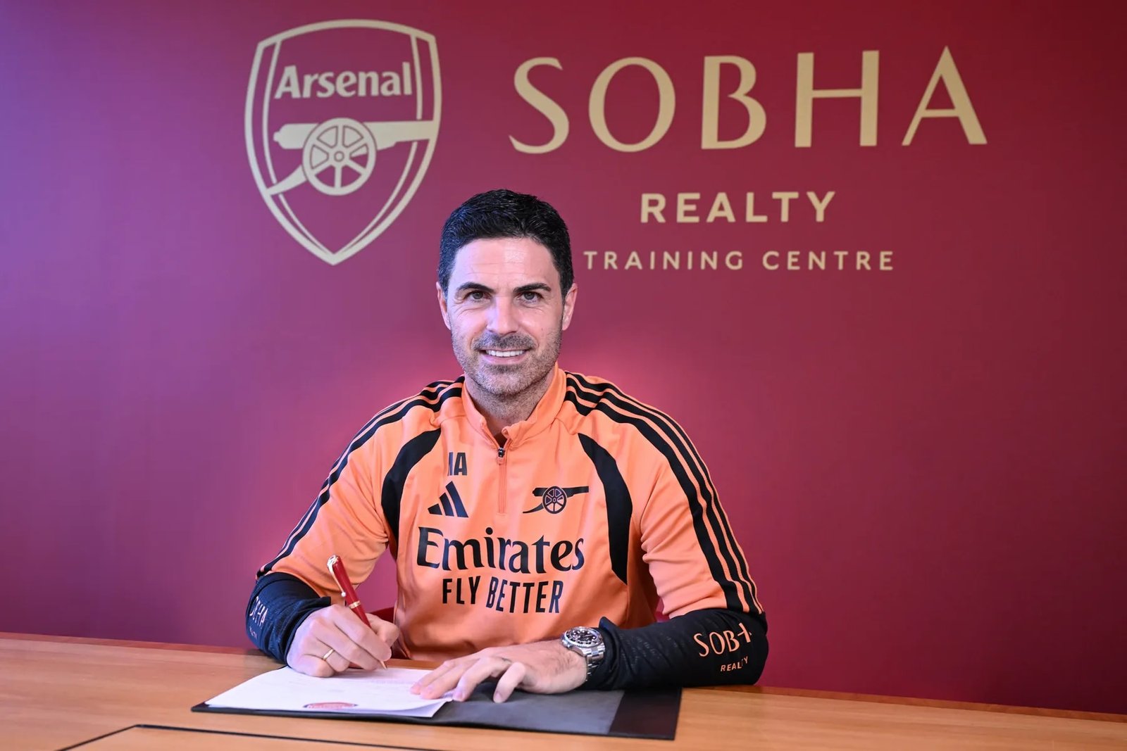 Mikel Arteta sentado ante un documento en el centro de entrenamiento del Arsenal