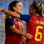 Dos futbolistas de España se abrazan; una viste la camiseta de Medina con el dorsal 6