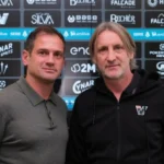 Dos hombres ante el panel de patrocinadores del Venezia FC