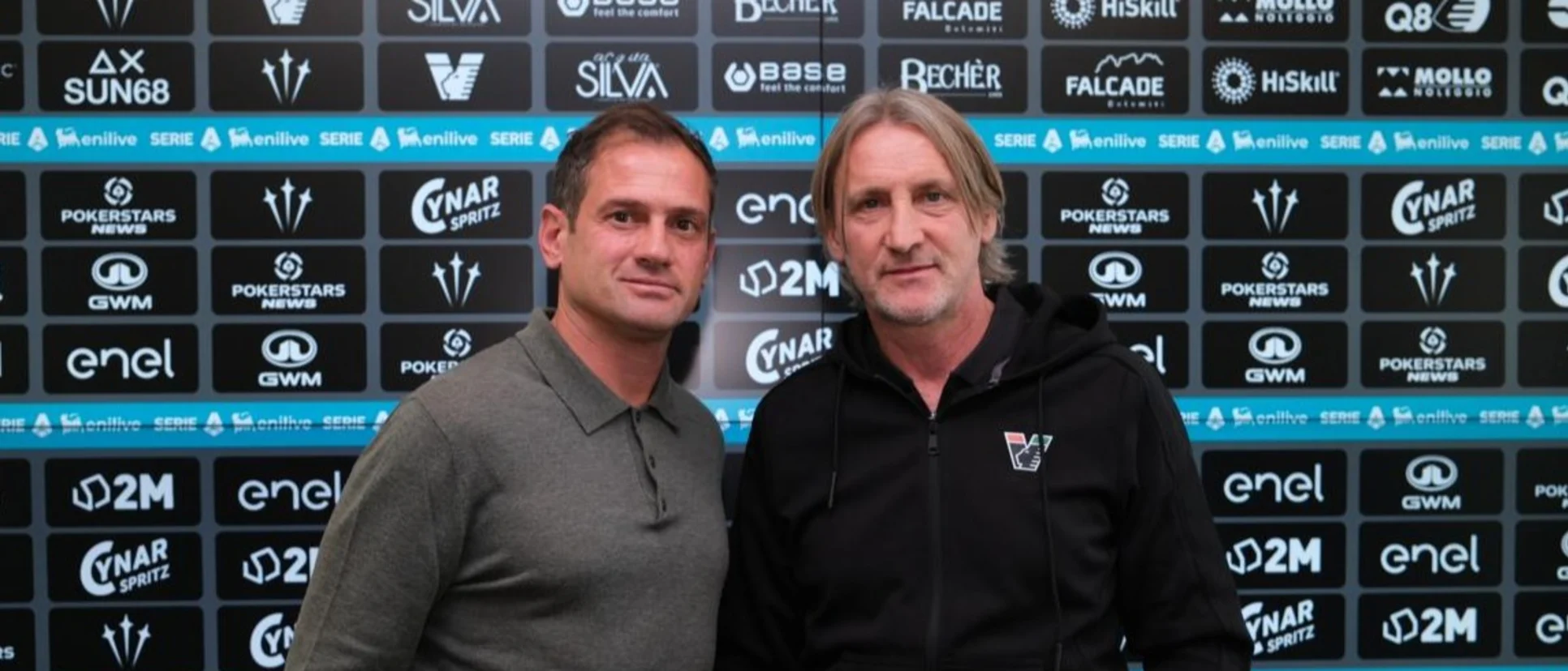 Dos hombres ante el panel de patrocinadores del Venezia FC