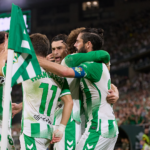 Varios jugadores del Betis se abrazan junto a un banderín de córner.