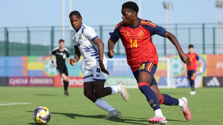 Futbolista de España con el dorsal 14 corre junto a un rival vestido de blanco.