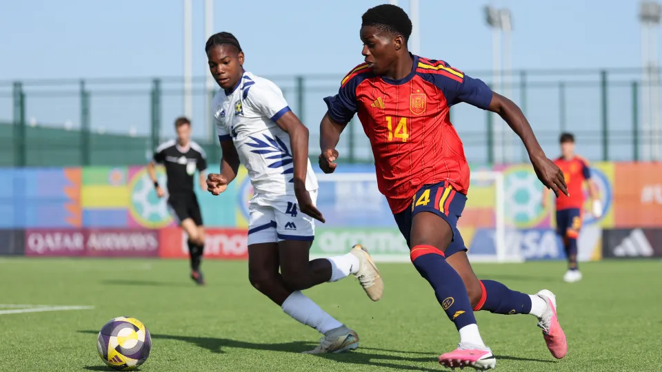 Futbolista de España con el dorsal 14 corre junto a un rival vestido de blanco.