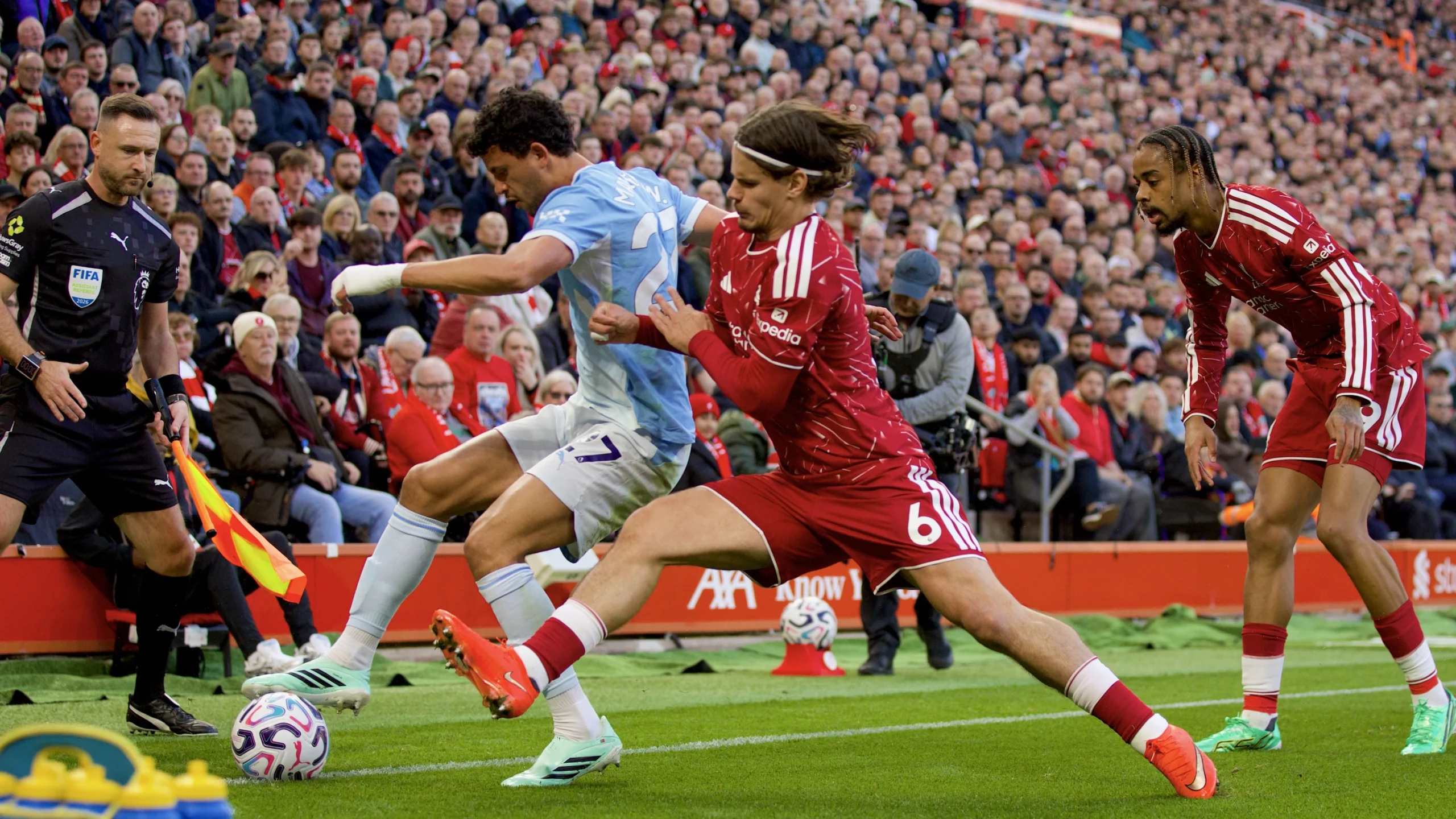 Jugador del Manchester City disputa el balón con futbolistas del Liverpool en Anfield
